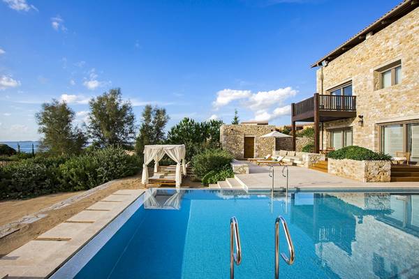 Der Westin Resort, Costa Navarino, zeigt einen Swimmingpool und eine Lounge-Ecke mit einem Baldachin und Sonnenliegen.