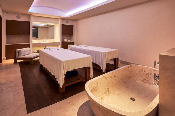 Spa-Behandlungsraum im Westin Resort, Costa Navarino mit zwei Massagetischen und einer Badewanne.