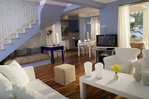 Wohnzimmer im Domes of Elounda, Autograph Collection mit Sofas, Tisch und Fernseher.