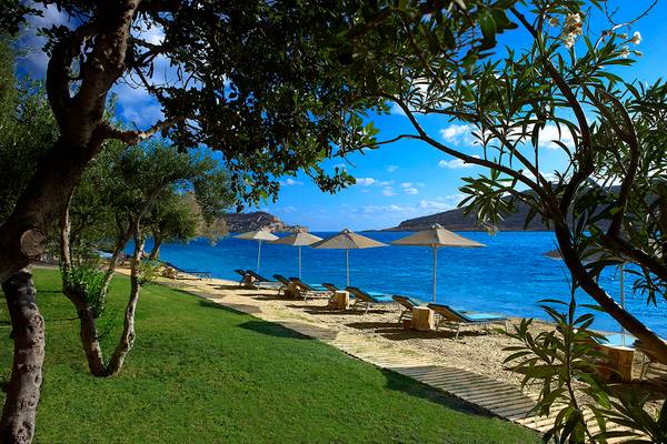 Strand des Domes of Elounda, Autograph Collection mit Sonnenliegen und Sonnenschirmen