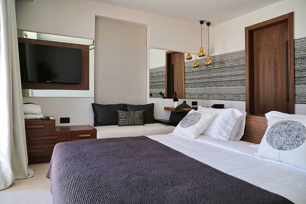 Schlafzimmer des Domes of Elounda, Autograph Collection mit Bett, Fernseher und Deko.