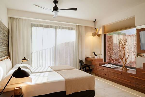 Doppelzimmer im Domes of Elounda, Autograph Collection mit zwei Betten und Blick auf die Außenlandschaft.