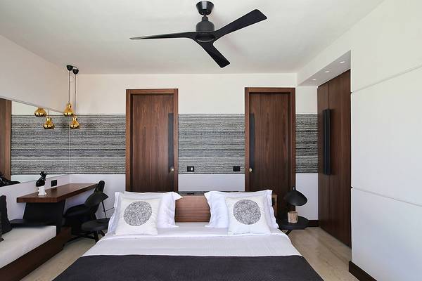 Schlafzimmer im Domes of Elounda, Autograph Collection mit einem Bett, zwei Kissen und einem Ventilator.