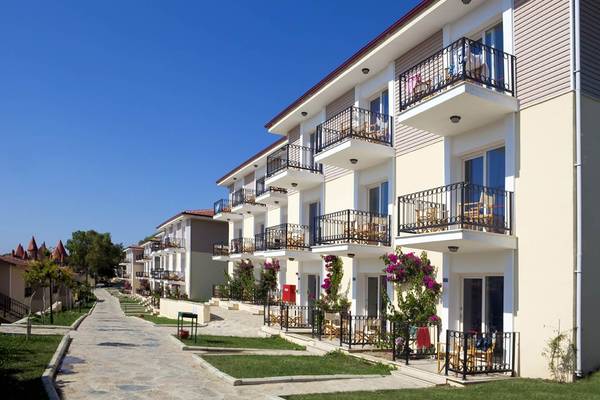 Außenansicht des Club Resort Atlantis mit mehreren Balkonen, blühenden Pflanzen und einer Allee.