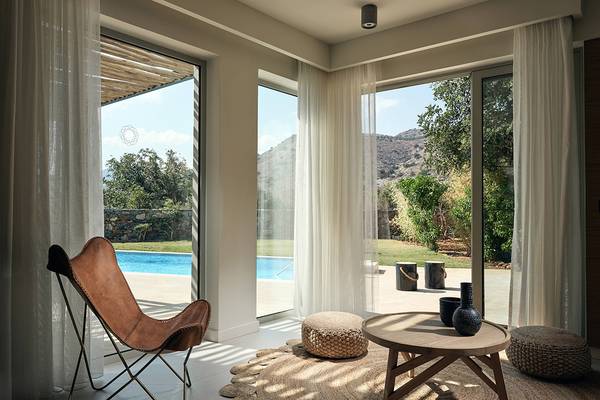 Innenansicht einer Suite im Domes of Elounda, Autograph Collection mit Blick auf einen Pool.