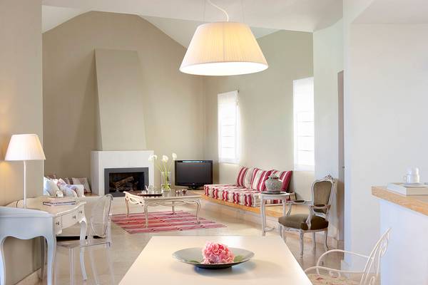Wohnbereich im Domes of Elounda, Autograph Collection mit Kamin, Sofa, Fernseher und Tisch mit Blume.