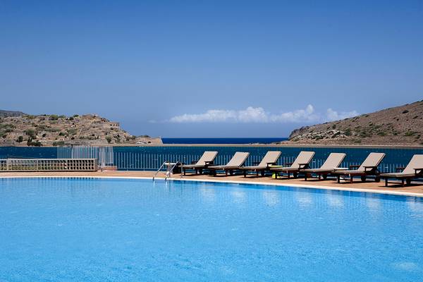 Pool am Domes of Elounda mit Blick auf das Meer und Hügel im Hintergrund