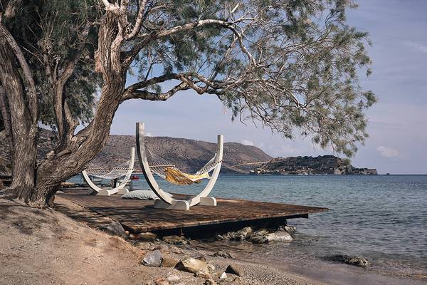 Zwei weiße Hängematten unter einem Baum am Strand im Domes of Elounda, Autograph Collection.