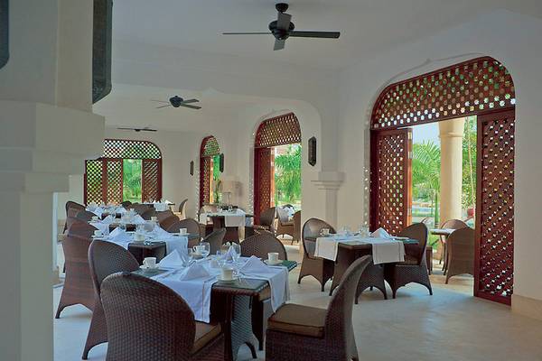 Innenansicht des Restaurants im Swahili Beach Resort mit gedeckten Tischen und Holzstühlen.