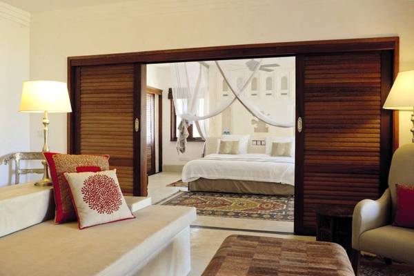 Schlafzimmer im Swahili Beach Resort mit Sofa, Bett und offenem Fenster.