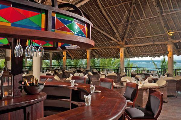 Innenansicht des Restaurants im Swahili Beach Resort mit Blick auf das Meer und bunten Glasfenstern.
