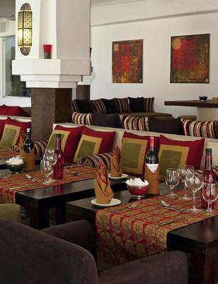 Interieur des Swahili Beach Resort Restaurants mit roten und grünen Kissen, Weinflaschen und Tischdecken.