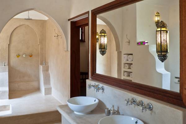Badezimmer im Swahili Beach Resort mit zwei Waschbecken, einem Spiegel und einer Dusche.