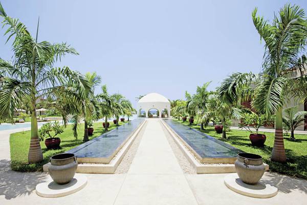 Gartenweg zum Gebäude des Swahili Beach Resorts mit Wasserläufen und Palmen