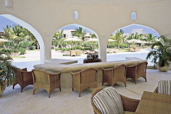 Terrasse des Swahili Beach Resorts mit Sofas und einem Tisch in einer tropischen Umgebung.