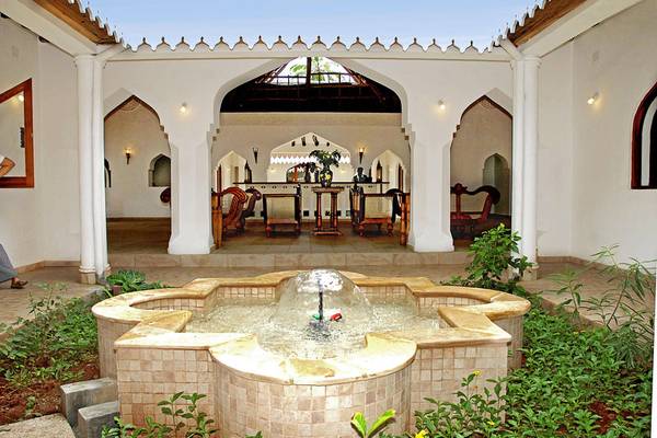Gartenbereich des Sultan Sands Island Resorts mit einem Wasserbrunnen und traditionellen Möbeln.
