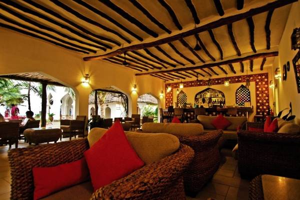 Loungebereich im Sultan Sands Island Resort mit braunen Sofas und roten Kissen.