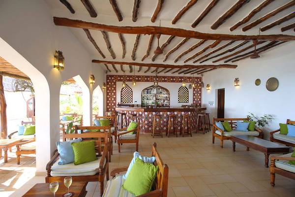Innenbereich des Sultan Sands Island Resorts mit Holzmöbeln, einer Bar und dekorativen Wandmustern.