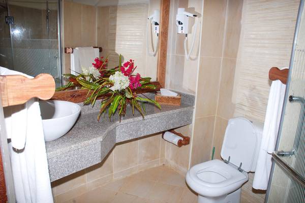 Badezimmer mit Waschbecken, Blumen, Toilette und Haartrocknern im Sultan Sands Island Resort.