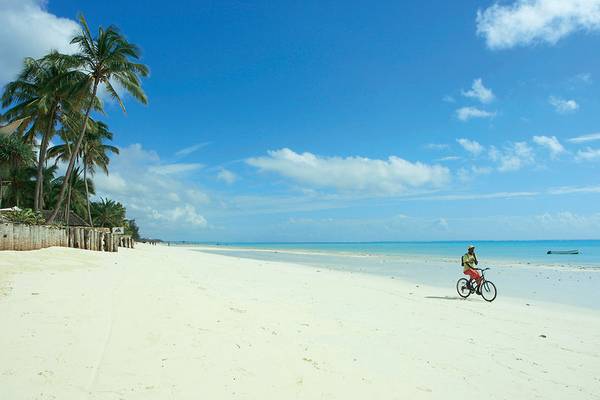 Eine Person fährt auf einem Fahrrad auf dem Strand des Sultan Sands Island Resorts.