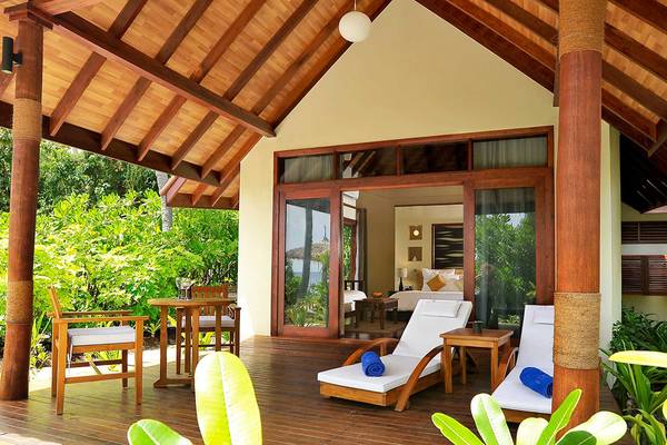 Villa-Terrasse im Robinson Maldives mit Lounge-Sesseln, Tisch und Aussicht auf den Ozean.