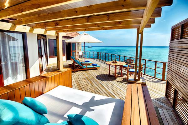 Terrasse des Robinson Maldives Hotels mit Blick auf das Meer und Sonnenschirm.
