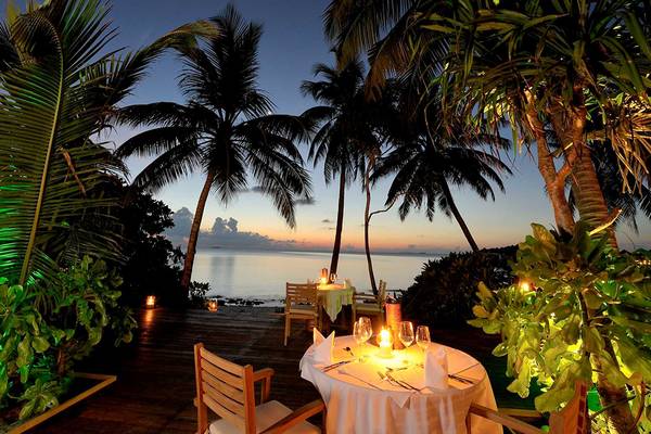 Außenbereich des Robinson Maldives mit Tisch und Kerzen bei Sonnenuntergang