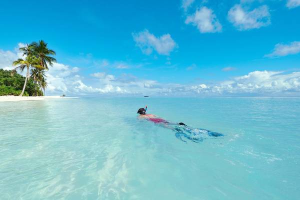 Eine Person schnorchelt im klaren Wasser vor Robinson Maldives.