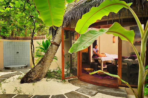 Eine Frau genießt eine Massage in einer Outdoor-Behandlungskabine im Robinson Maldives.