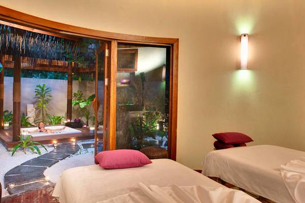 Spa-Behandlungsraum im Robinson Maldives Hotel mit einer Frau in einer Badewanne und zwei Behandlungsbetten.