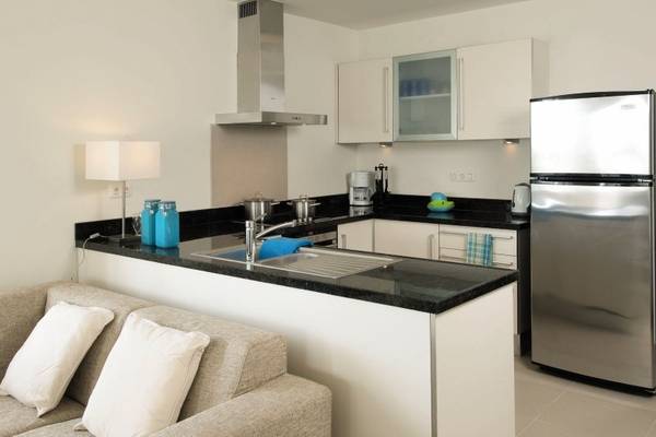 Inneneinrichtung der Küche im Blue Bay Curacao Golf & Beach Resort mit weißem Kühlschrank und schwarzem Granit-Arbeitsplatte.