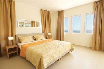 Ein Bettzimmer im Blue Bay Curacao Golf & Beach Resort mit zwei Fenstern, zwei Lampen und einem großen Bett.