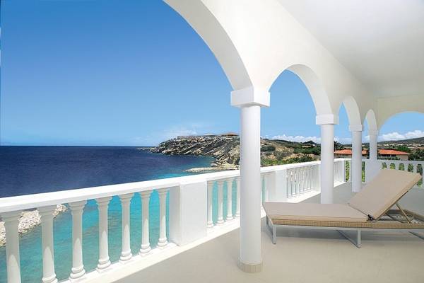 Balkon im Blue Bay Curacao Golf & Beach Resort mit Blick auf das Meer und eine Insel.