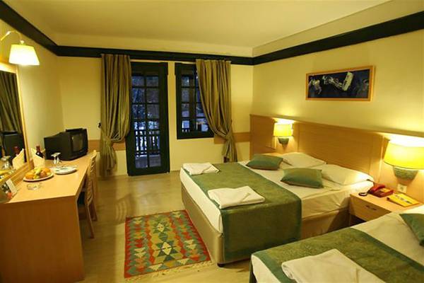 Hotelzimmer im Grand Yazici Club Marmaris Palace mit zwei Betten, Schreibtisch, Fernseher und Fenstern.