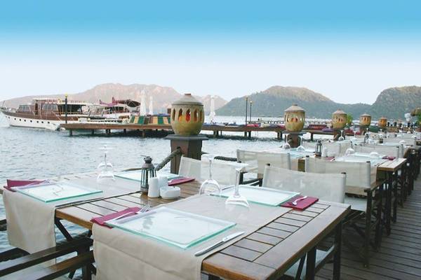 Terrasse des Grand Yazici Club Marmaris Palace mit Tischen und Stühlen am Wasser