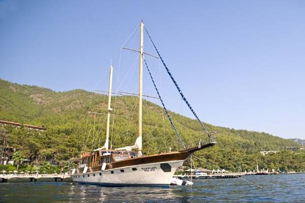 Ein Boot des Grand Yazici Club Marmaris Palace liegt im Wasser vor einer grünen Berglandschaft.