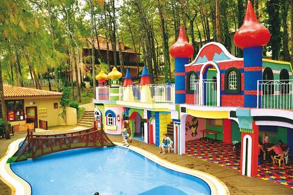 Kinderpool im Grand Yazici Club Marmaris Palace mit bunten Gebäuden und Bäumen.