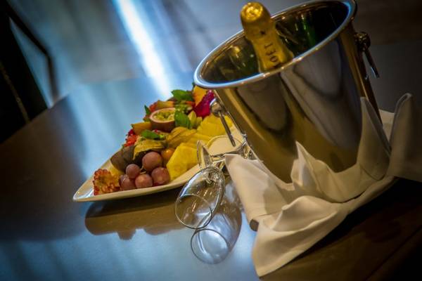 Eine Fruchtplatte und eine Flasche Champagner auf einem Tisch im Adams Beach Hotel.