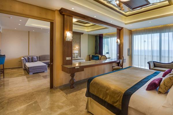Luxuriöses Schlafzimmer im Adams Beach Hotel mit Doppelbett, Sitzbereich und Spiegel.