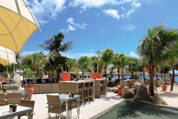 Strandbar des Van der Valk Kontiki Beach Resorts mit Tischen und Stühlen, Palmen und Meerblick