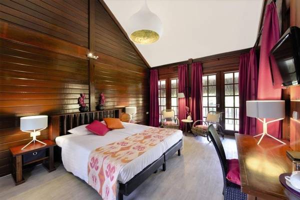 Hotelzimmer im Van der Valk Kontiki Beach Resort in Curaçao mit Holzwänden, einem großen Bett und einem Schreibtisch.