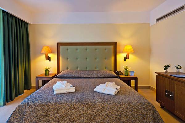 Hotelzimmer im Giannoulis Cavo Spada Sports & Leisure Resort mit Bett, Nachttischen und Lampen.