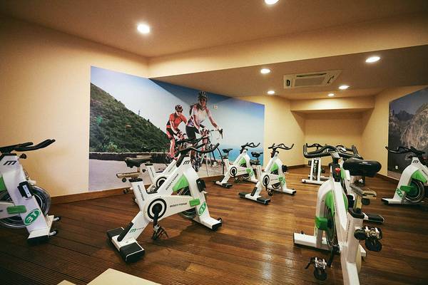 Fitnessraum im Giannoulis Cavo Spada Resort mit Spinrädern und einer großen Wandgrafik von Fahrradfahrern.