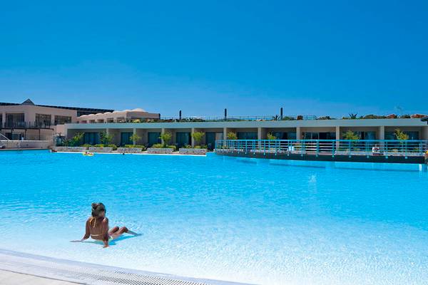 Eine Frau sitzt im Schwimmbad des Giannoulis Cavo Spada Sports & Leisure Resorts.