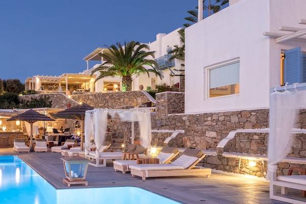 Vencia Boutique Hotel Poolbereich bei Nacht mit Steinmauer, Sonnenliegen und Schirmen.