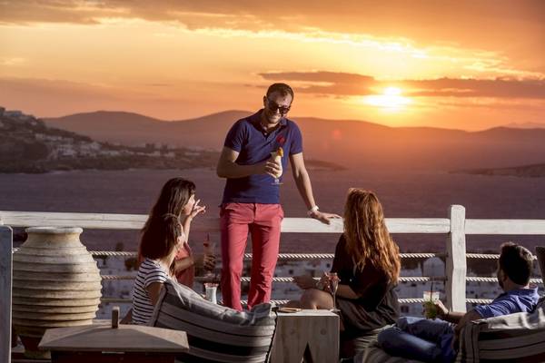 Vier Personen sitzen auf der Terrasse des Vencia Boutique Hotels und genießen den Sonnenuntergang.