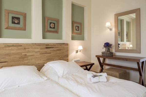 Schlafzimmer im Vencia Boutique Hotel mit zwei Betten, weißen Laken, Holzkopfteil und grünen Wänden.