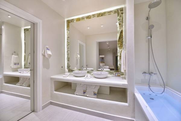 Badezimmer im Vencia Boutique Hotel mit Marmorfliesen und weißen Armaturen.