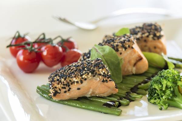 Portion Lachs auf einem Teller mit Gemüse und Kirschtomaten