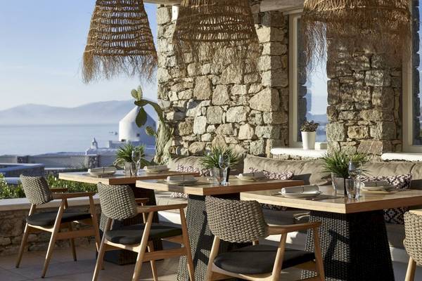 Terrasse des Vencia Boutique Hotels mit Tischen, Stühlen und Blick auf das Meer.